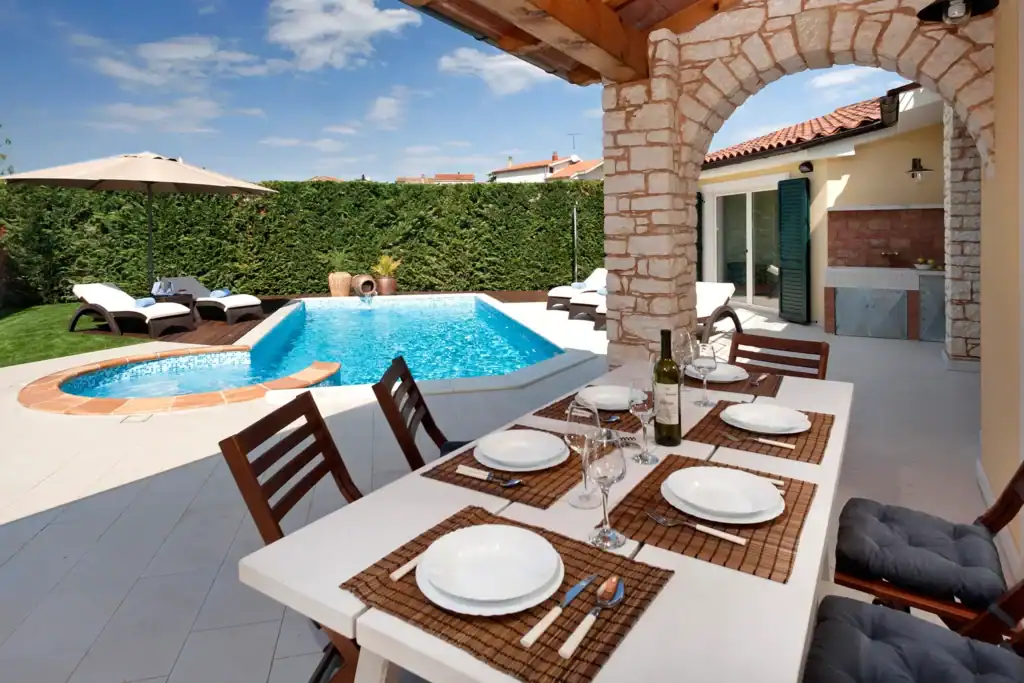 Gedeckter Tisch unter dem Steinbogen der Villa Santa Domenica mit Poolblick