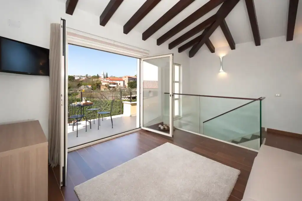 Sitzbereich der Villa Santa Domenica mit Holzbalken, Teppich und offener Balkontür