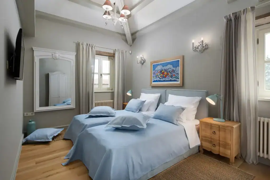 Schlafzimmer der Villa Elena mit hellblauem Bettüberwurf und Gemälde