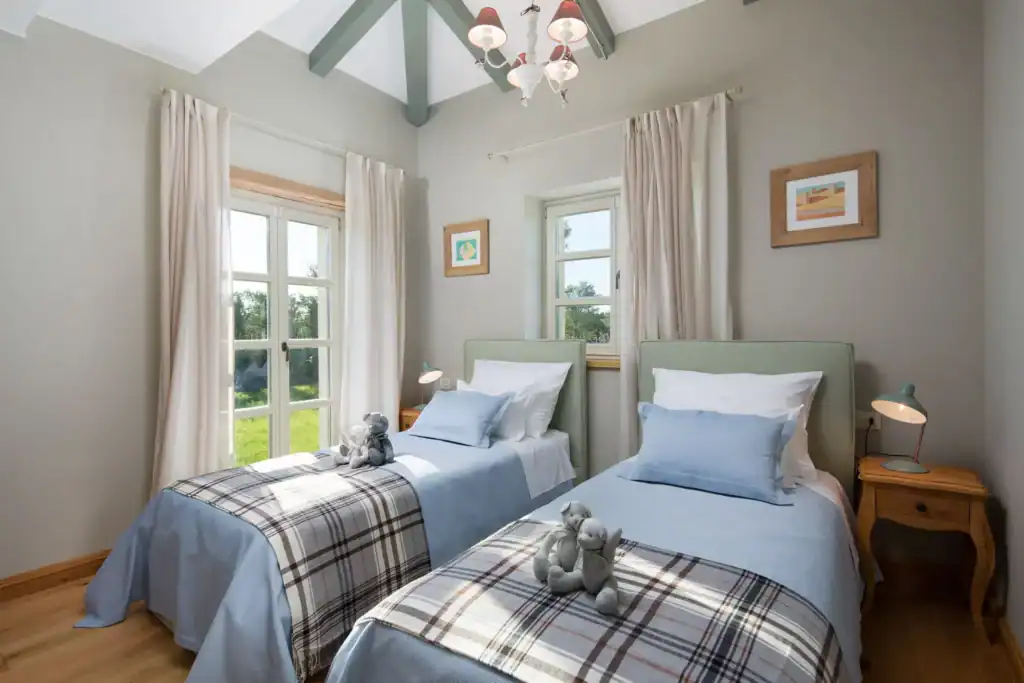 Schlafzimmer der Villa Nevia mit zwei Einzelbetten und karierten Decken