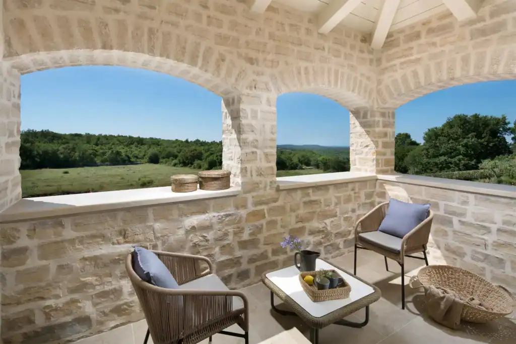 Loggia der Villa Nevia mit Steinbögen, Sesseln und Blick ins Grüne