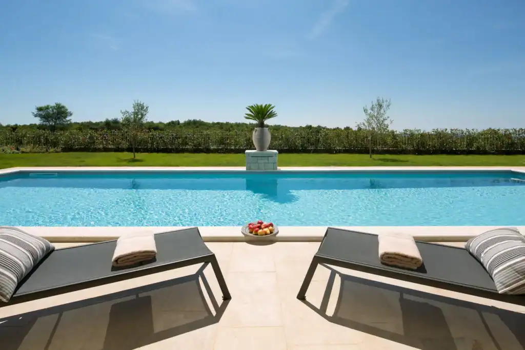 Pool der Villa Nevia mit zwei Sonnenliegen und Obstschale