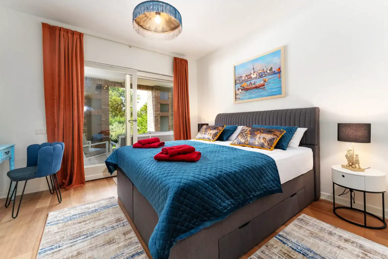 Villa Lionea 52 Schlafzimmer der Villa Lionea mit blauem Bettüberwurf und orangefarbenen Vorhängen