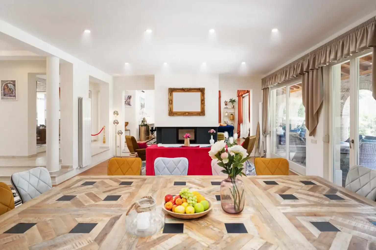 Villa Lionea 44 Esstisch der Villa Lionea mit Obstschale, Blumenvase und bunten Stühlen