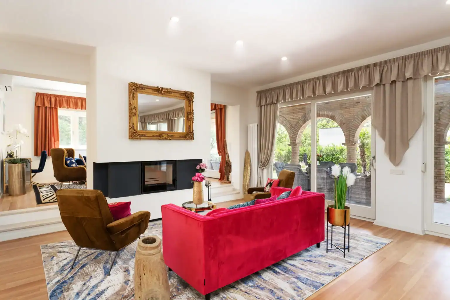 Villa Lionea 43 Wohnzimmer der Villa Lionea mit rotem Samtsofa, Kamin und Goldspiegel