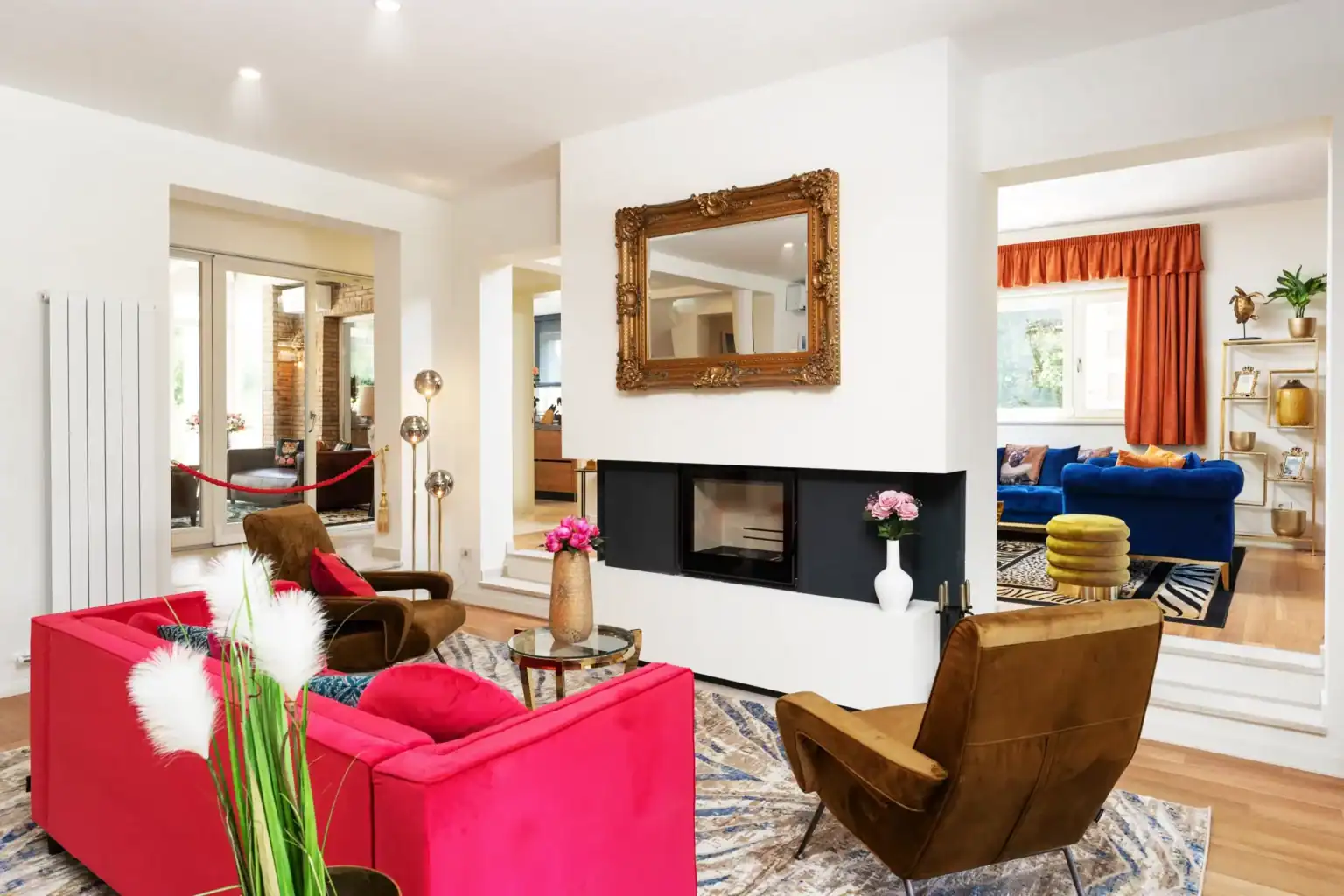 Villa Lionea 41 Wohnzimmer der Villa Lionea mit Kamin, rotem Sofa und braunen Sesseln