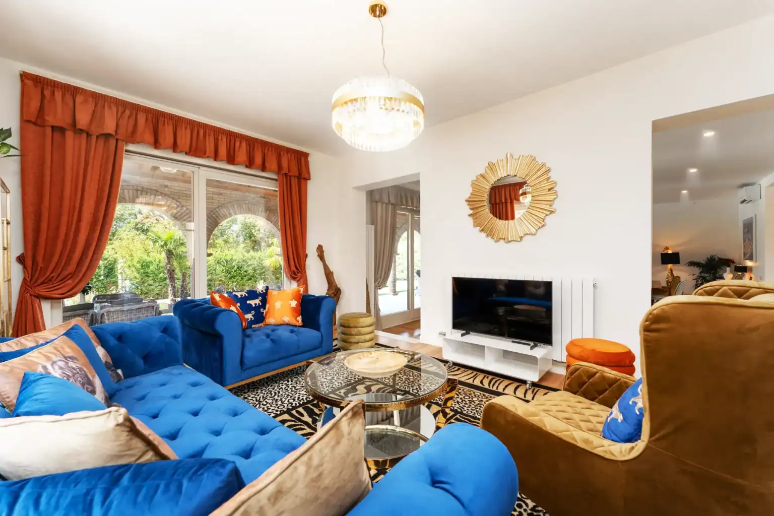 Villa Lionea 39 Wohnzimmer der Villa Lionea mit blauem Sofa, Fernseher und Sonnenspiegel