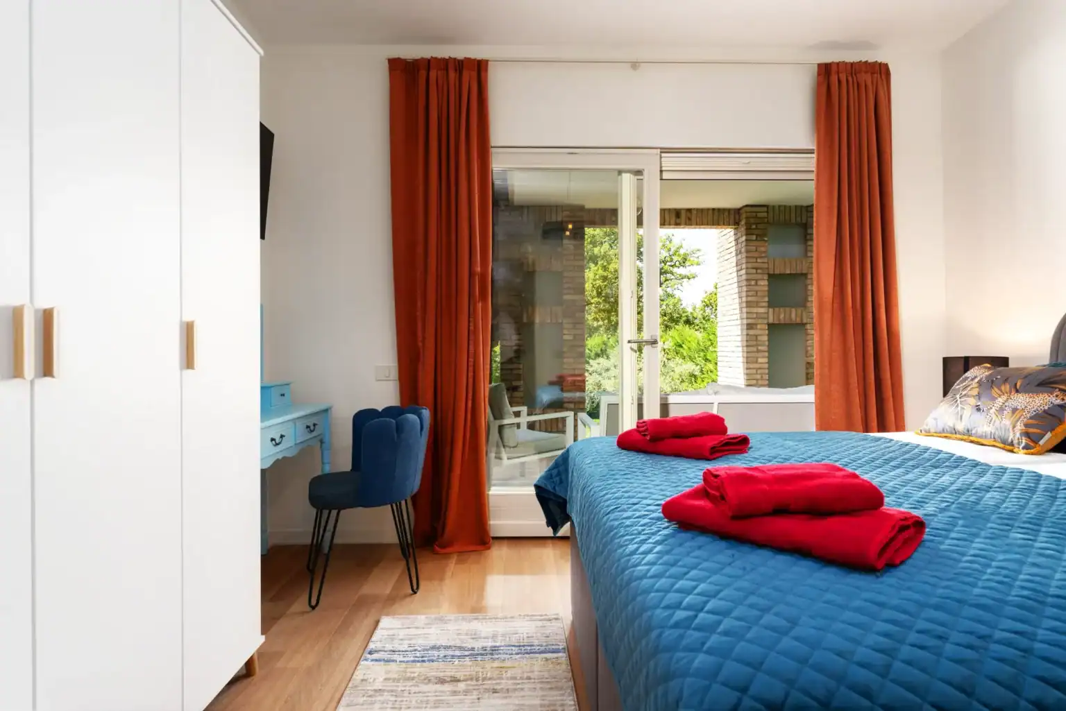 Villa Lionea 33 Schlafzimmer der Villa Lionea mit blauem Bettüberwurf, Kleiderschrank und Terrassentür