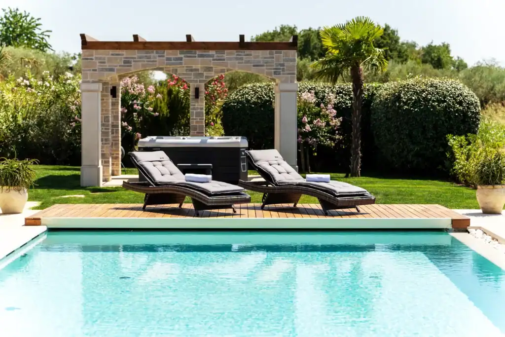 Pool der Villa Kastelir mit zwei Liegen vor steinerner Pergola mit Whirlpool