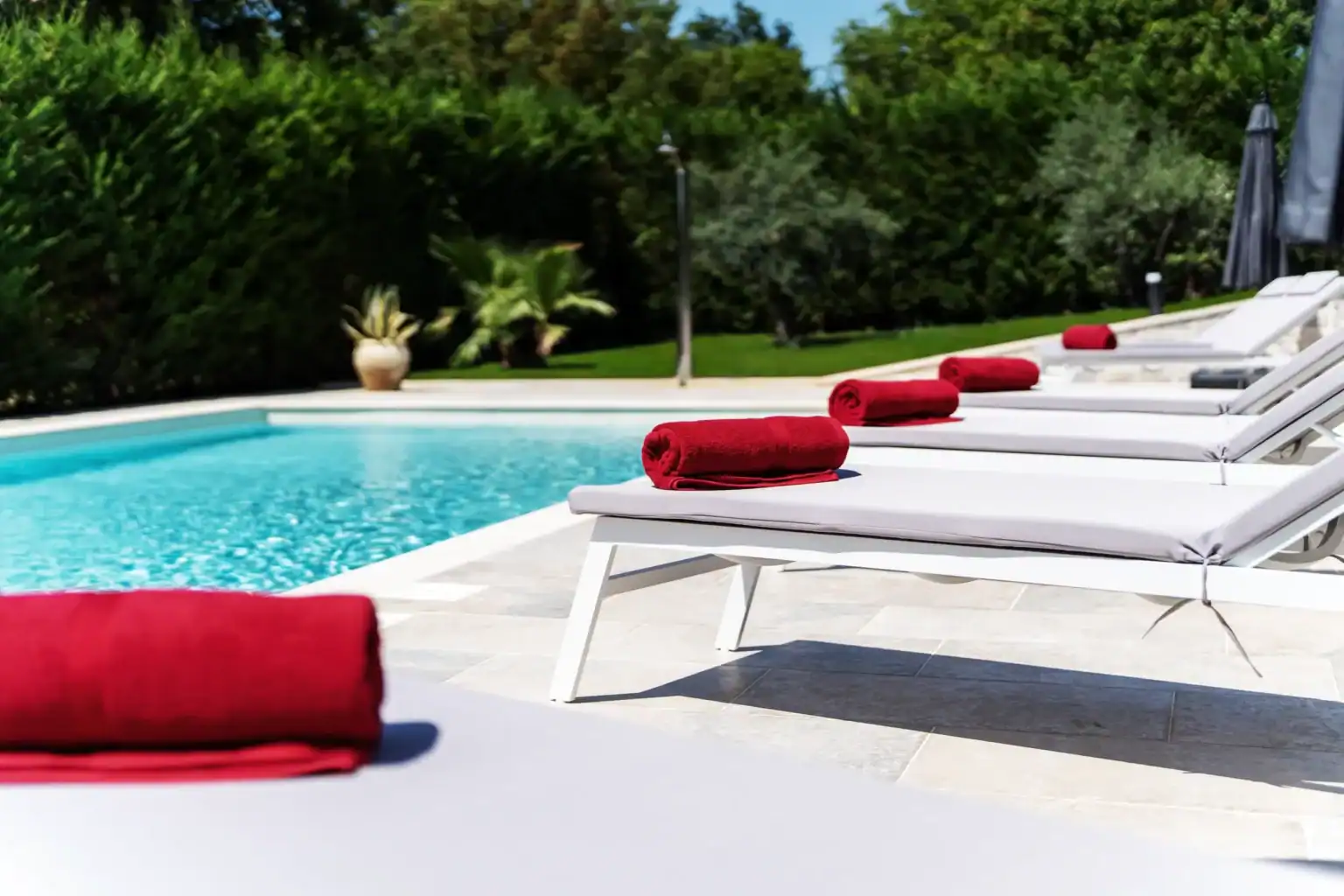 Villa Lionea 31 Pool der Villa Lionea mit weißen Sonnenliegen und roten Handtüchern