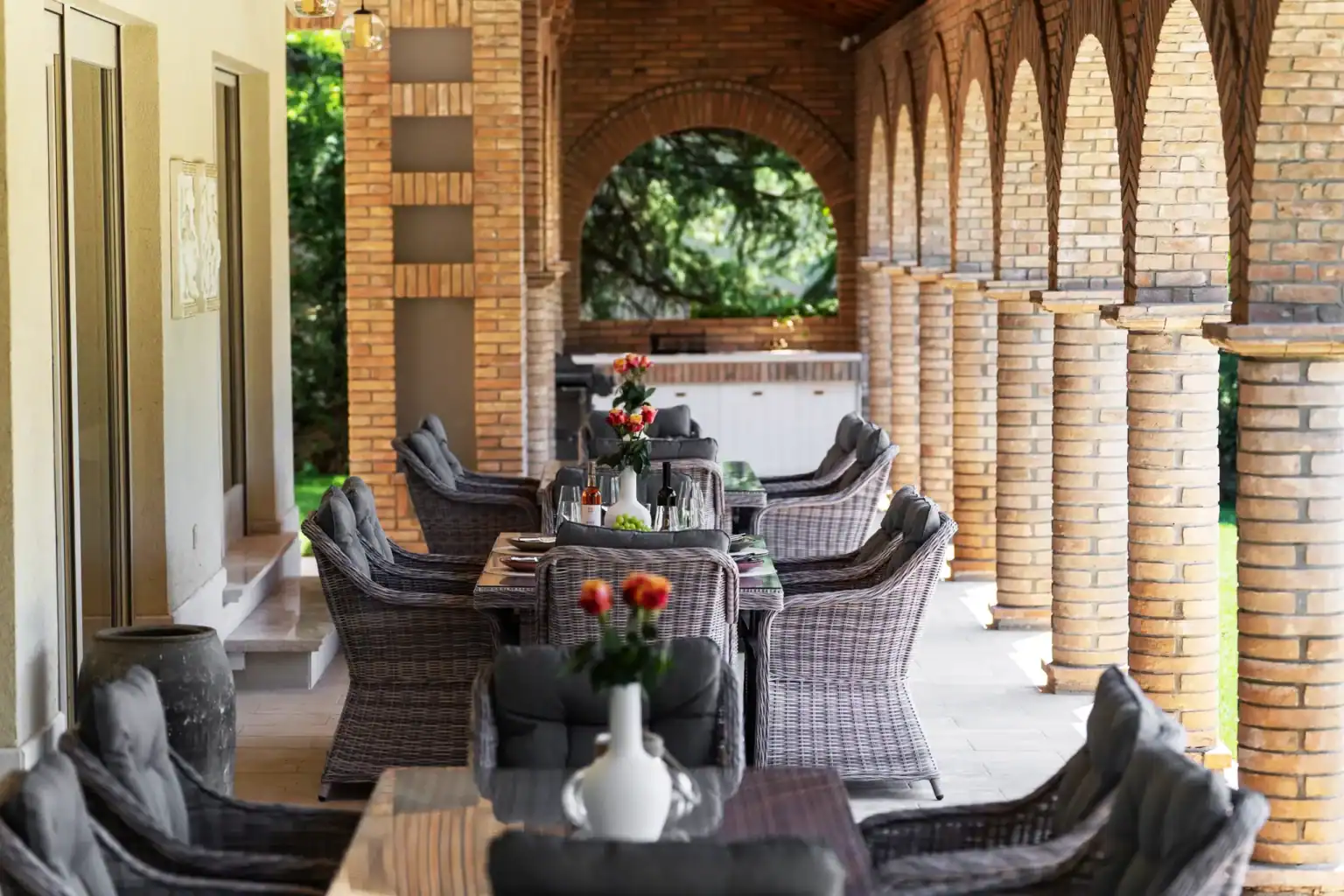 Villa Lionea 30 Überdachte Terrasse der Villa Lionea mit Ziegelbögen und Rattan-Sitzgruppen