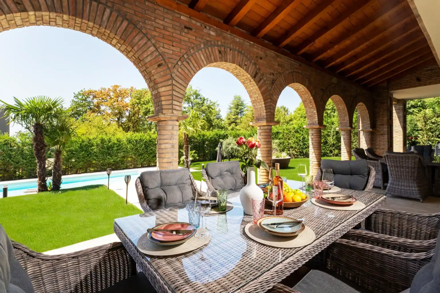 Villa Lionea 28 Überdachte Terrasse der Villa Lionea mit Holzdecke, Ziegelbögen und Poolblick