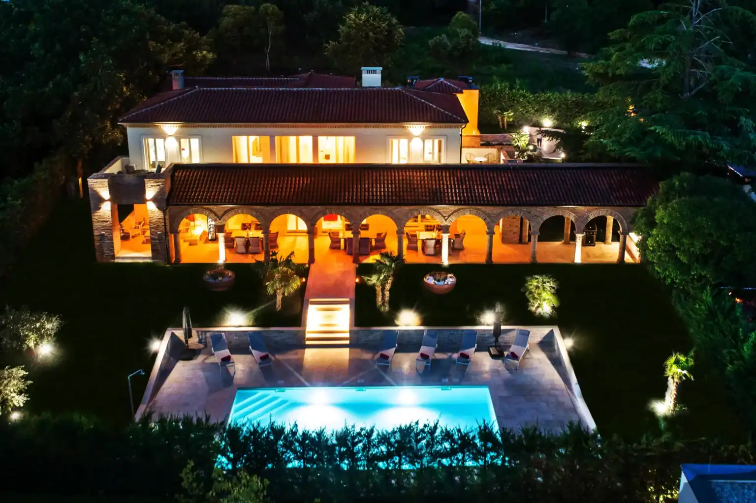 Villa Lionea 20 Außenansicht der Villa Lionea bei Nacht mit beleuchtetem Pool und Bogengang