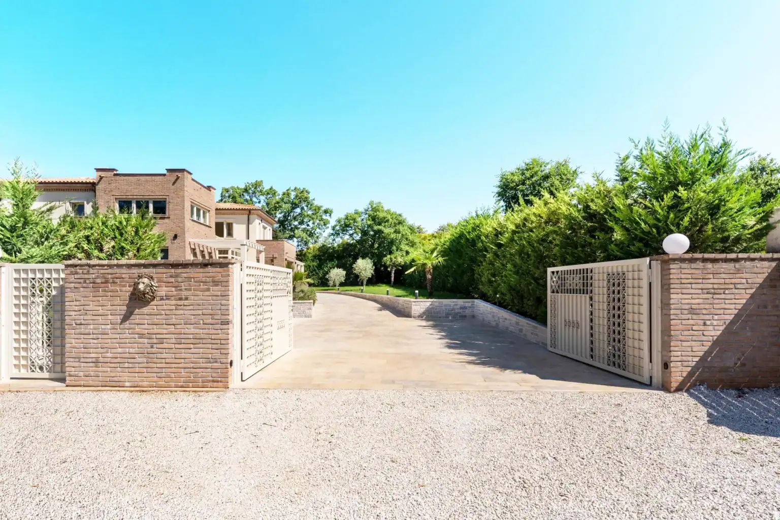 Villa Lionea 17 Einfahrt der Villa Lionea mit Kiesfläche, Toren und Ziegelmauern
