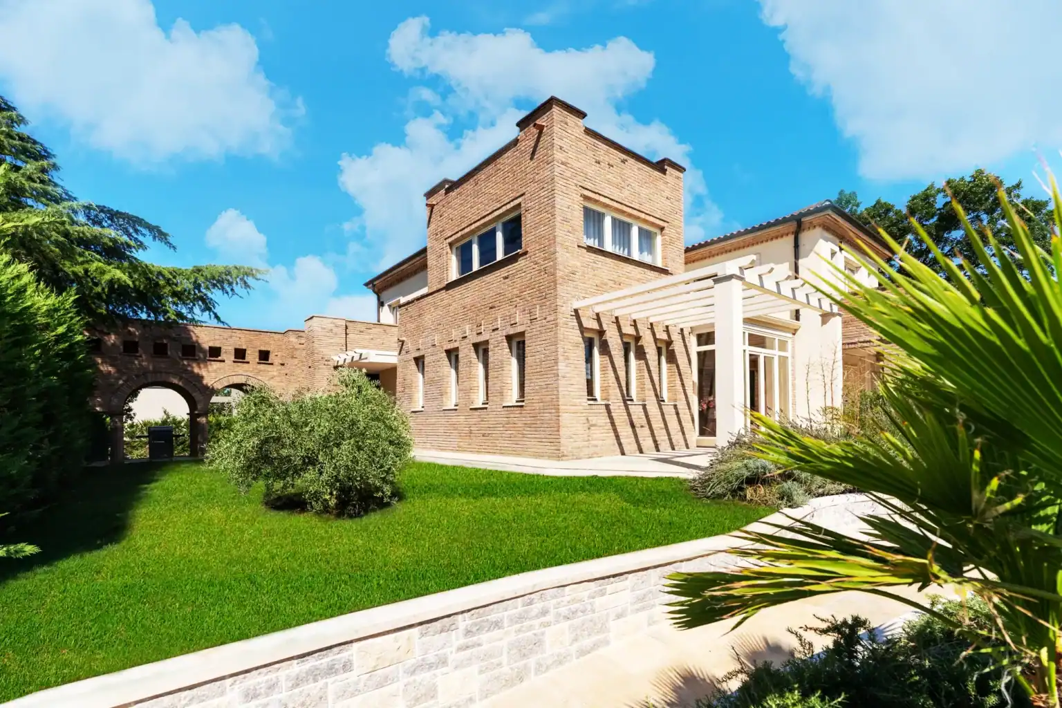 Villa Lionea 16 Außenansicht der Villa Lionea mit Klinkerfassade, Pergola und Rasen