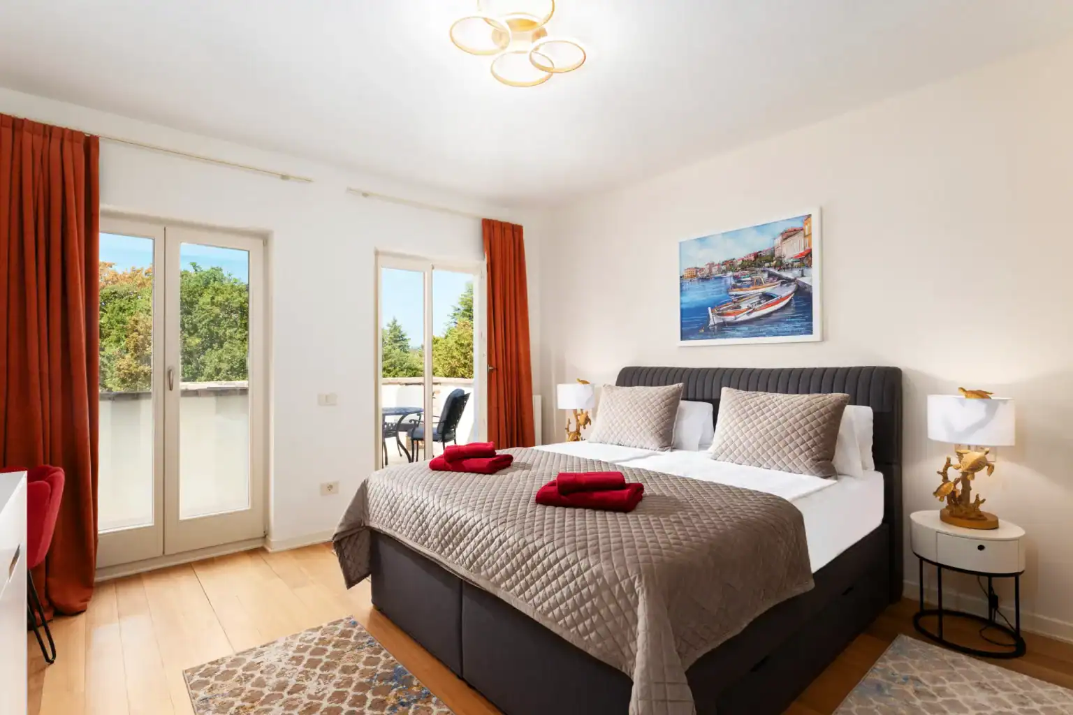 Villa Lionea 15 Schlafzimmer der Villa Lionea mit beigem Bettüberwurf und zwei Balkontüren