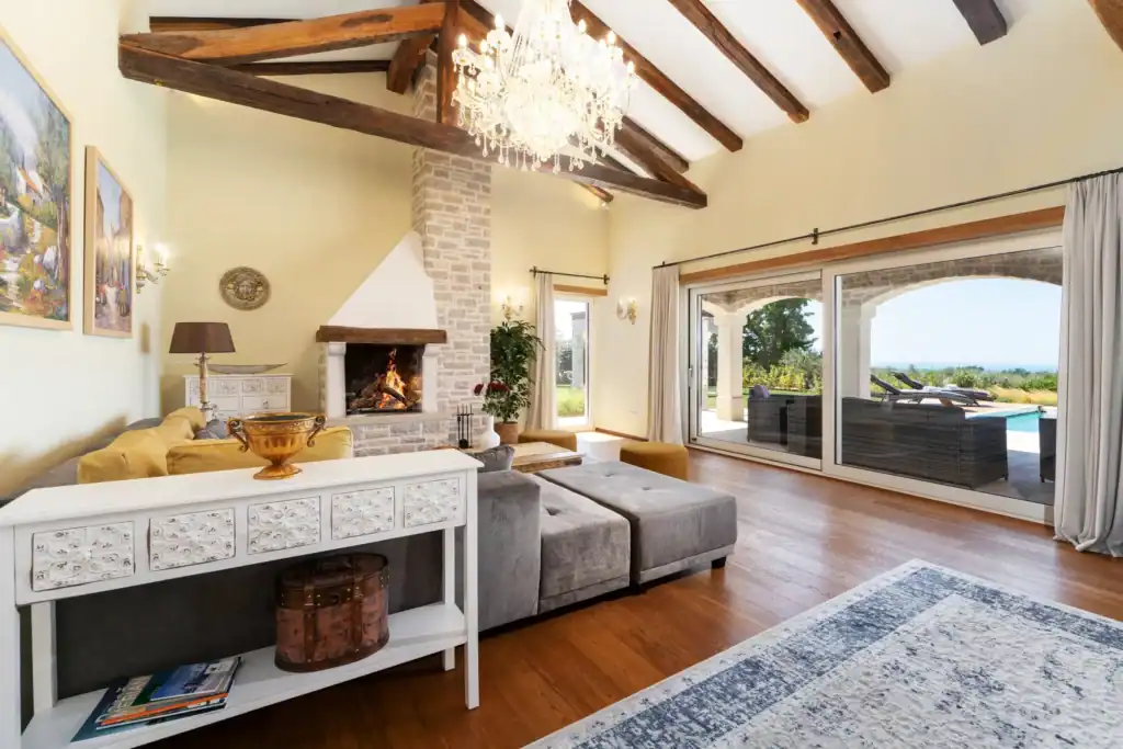 Wohnzimmer der Villa Kastelir mit Kamin, grauem Sofa und Glasfront