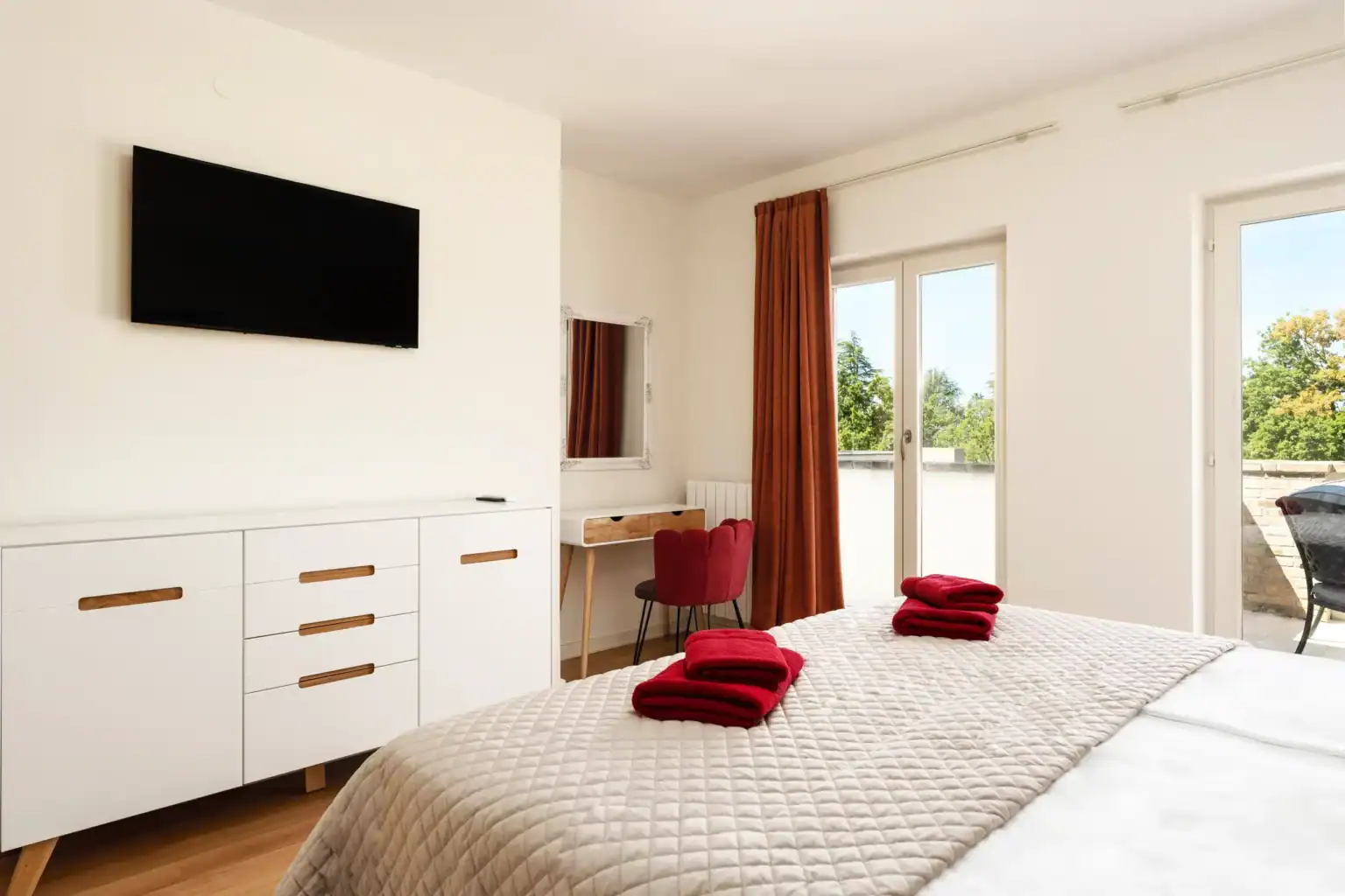 Villa Lionea 14 Schlafzimmer der Villa Lionea mit beigem Überwurf, Sideboard und Fernseher