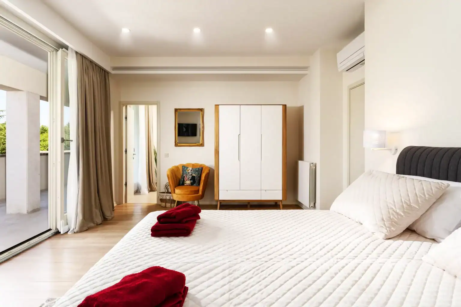 Villa Lionea 10 Schlafzimmer der Villa Lionea mit weißer Tagesdecke, Kleiderschrank und Glasfront