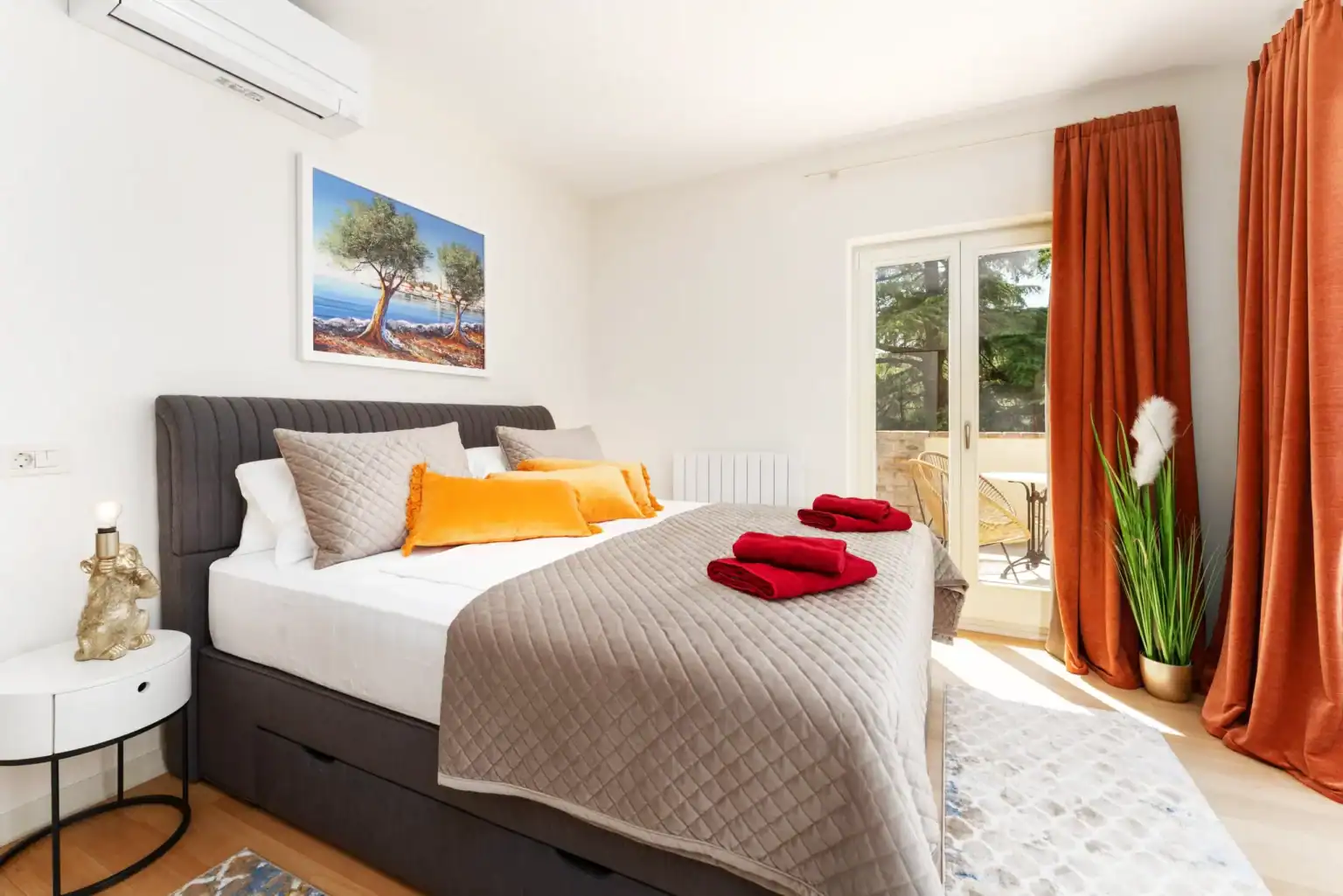 Villa Lionea 8 Schlafzimmer der Villa Lionea mit Olivenbaum-Gemälde und orangefarbenen Kissen