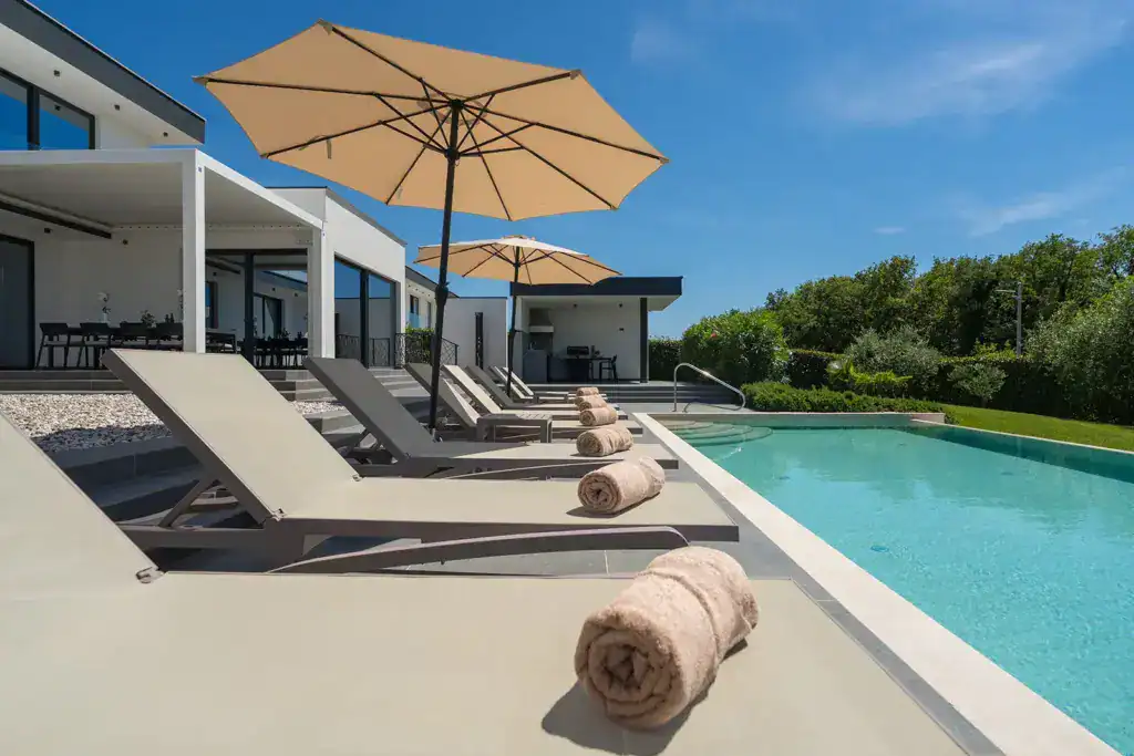 Pool der Villa Nura mit Sonnenliegen, Handtuch und Blick zur Terrasse